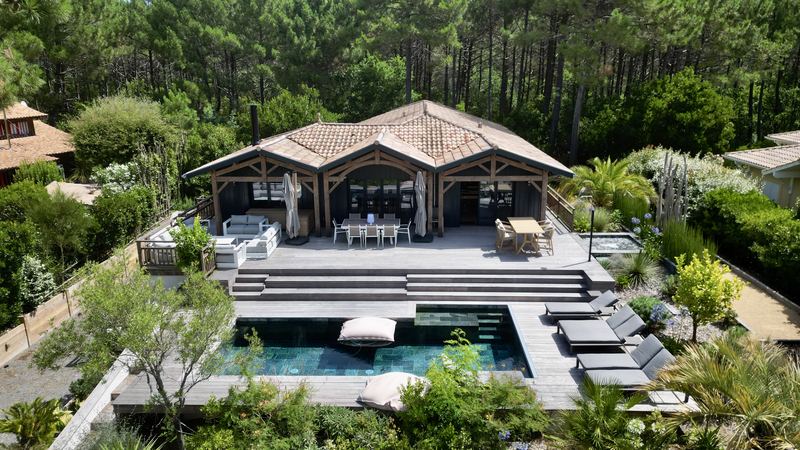 Villa avec terrasse et piscine entourée de végétation, vue aérienne par drone