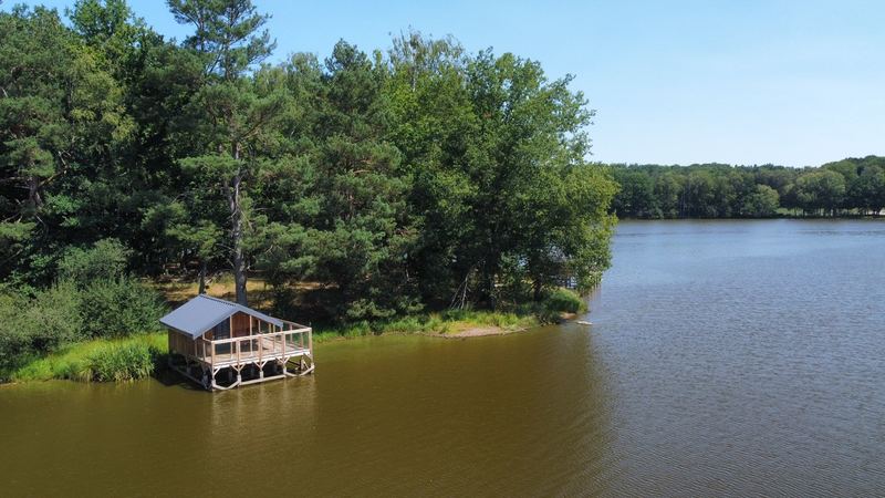 Cabane en bois au bord d'un lac, vue aérienne par drone