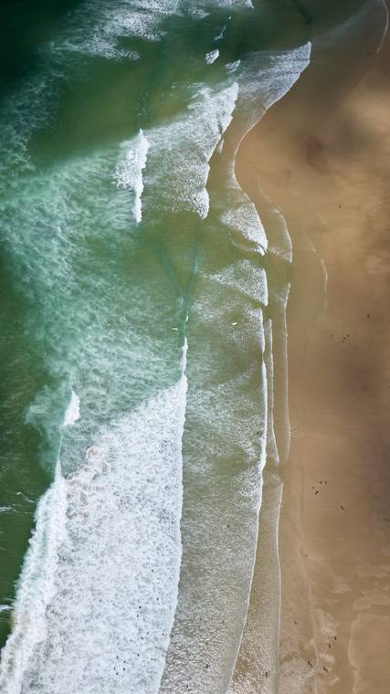 Rouleaux de l'océan sur une plage de sable, vue verticale par drone