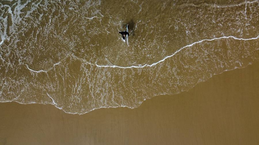 Surfeur entrant dans l'eau, vue verticale par drone